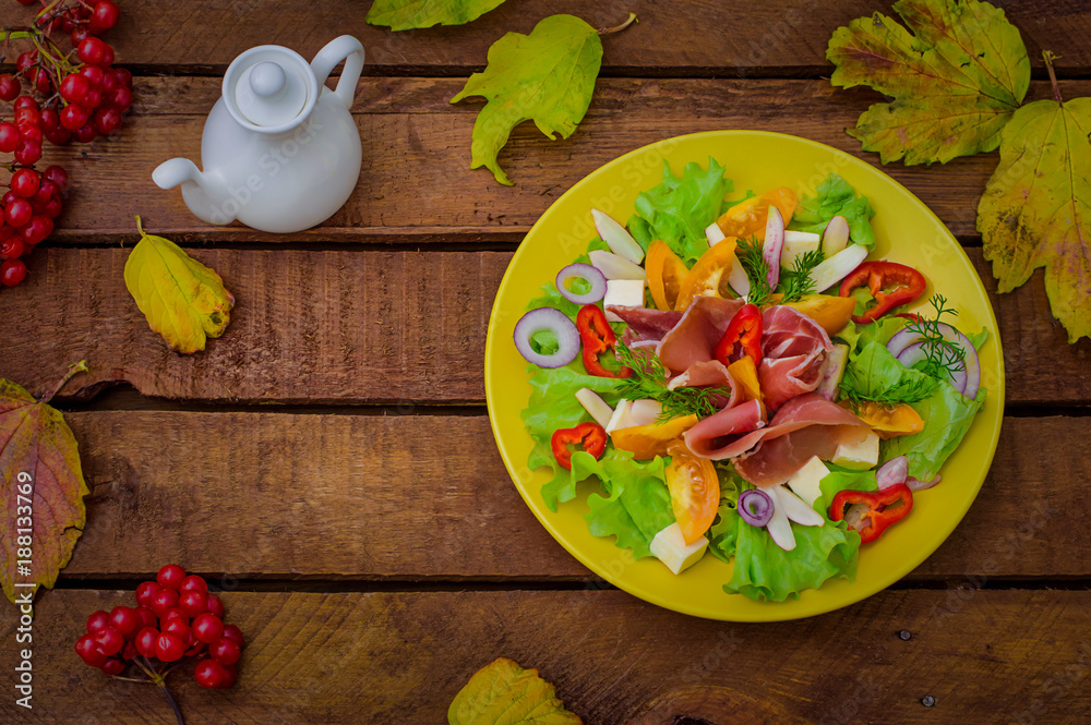 Autumn salad of jamon, lettuce, tomatoes, cheese. Wooden rustic background. Selective focus. Top view