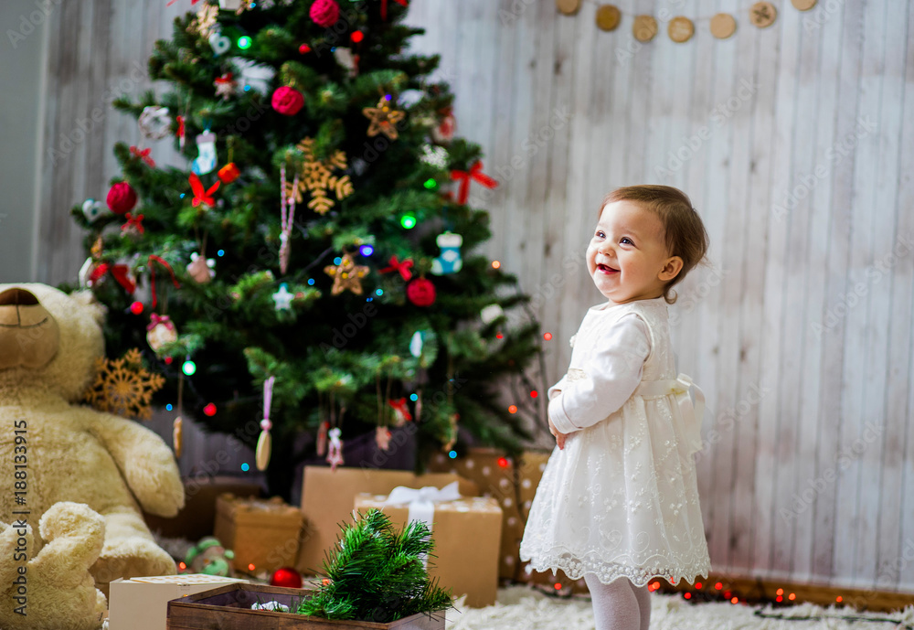 A cute little baby poses near a Christmas tree