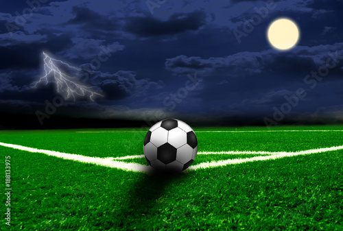 Soccer field under the night sky with the moon and lightning