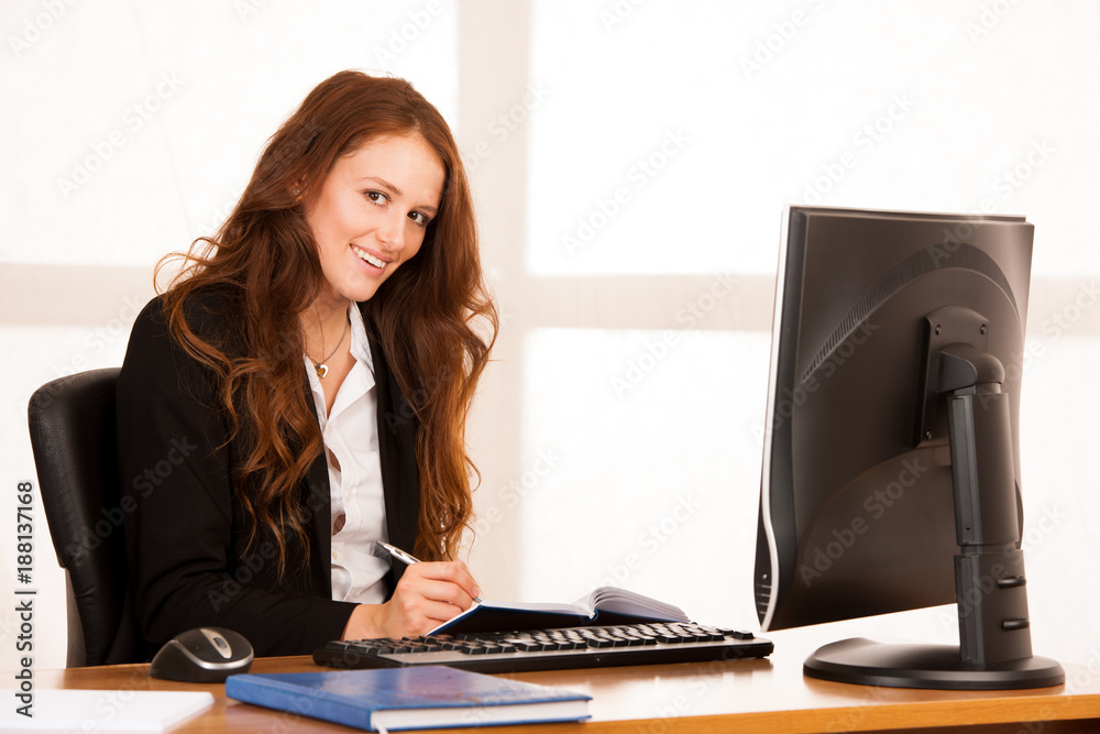 beautiful young business woman work at her desk in the office with window in the background beautiful young business woman work at her desk in the office with window in the background