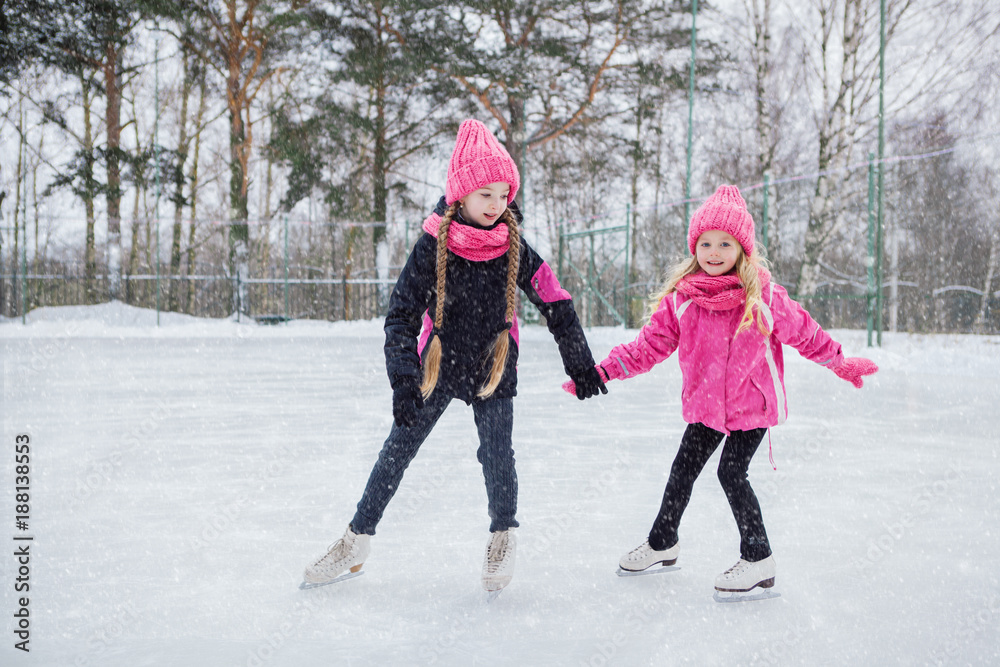 Φωτογραφία Two Little smiling girls skating on ice in pink wear.