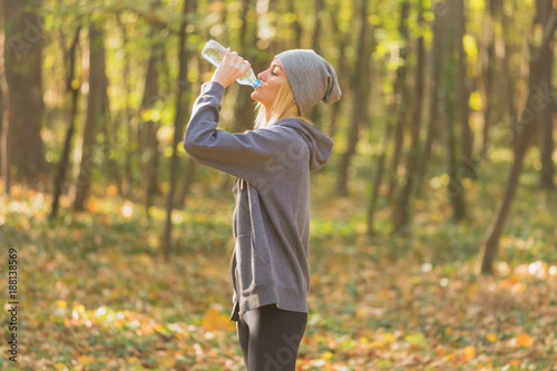 runner woman drinking water in the park © Milica