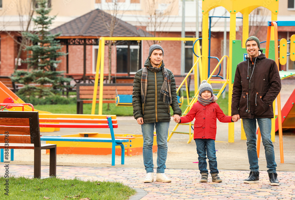 Male gay couple with adopted boy at playground