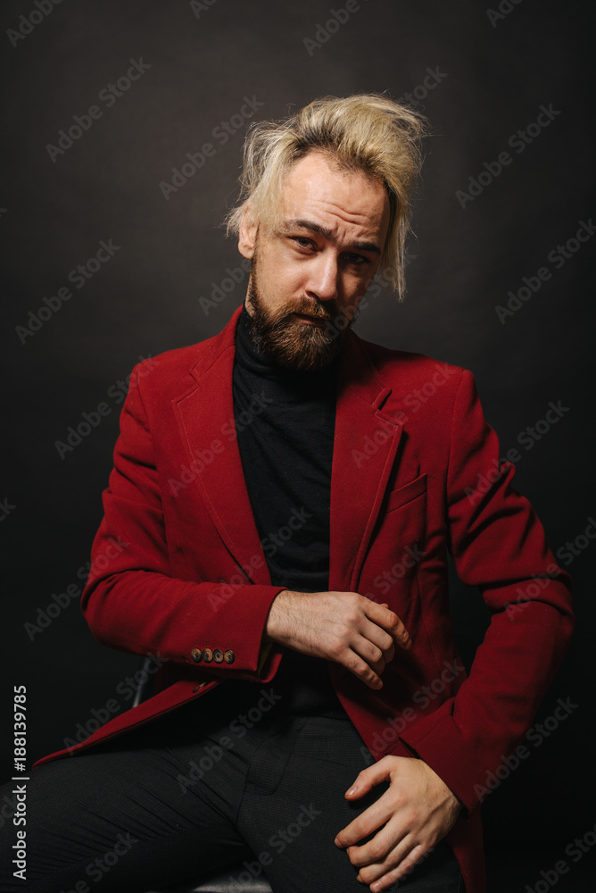 Theater of the idea. Close-up of a young handsome man in a red jacket and black golf. Advertising photography. Beard for a barbershop.