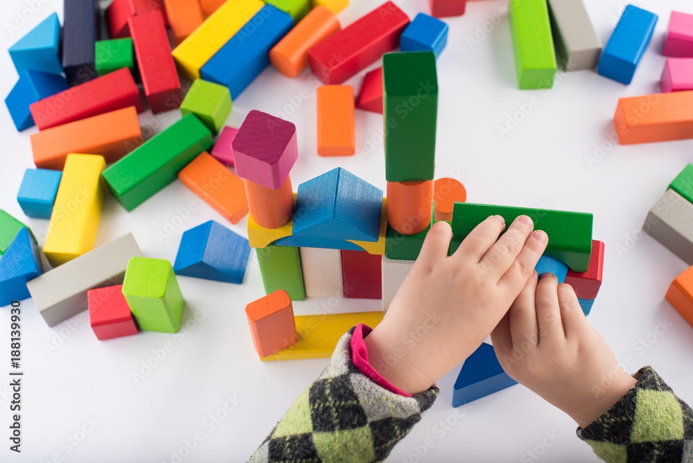 Four year old girl plays in the designer. Wooden toys, colorful children's designer on white background, entertainment with a kid, development of preschoolers, construction Four year old girl plays in the designer. Wooden toys, colorful children's designer on white background, entertainment with a kid, development of preschoolers, construction