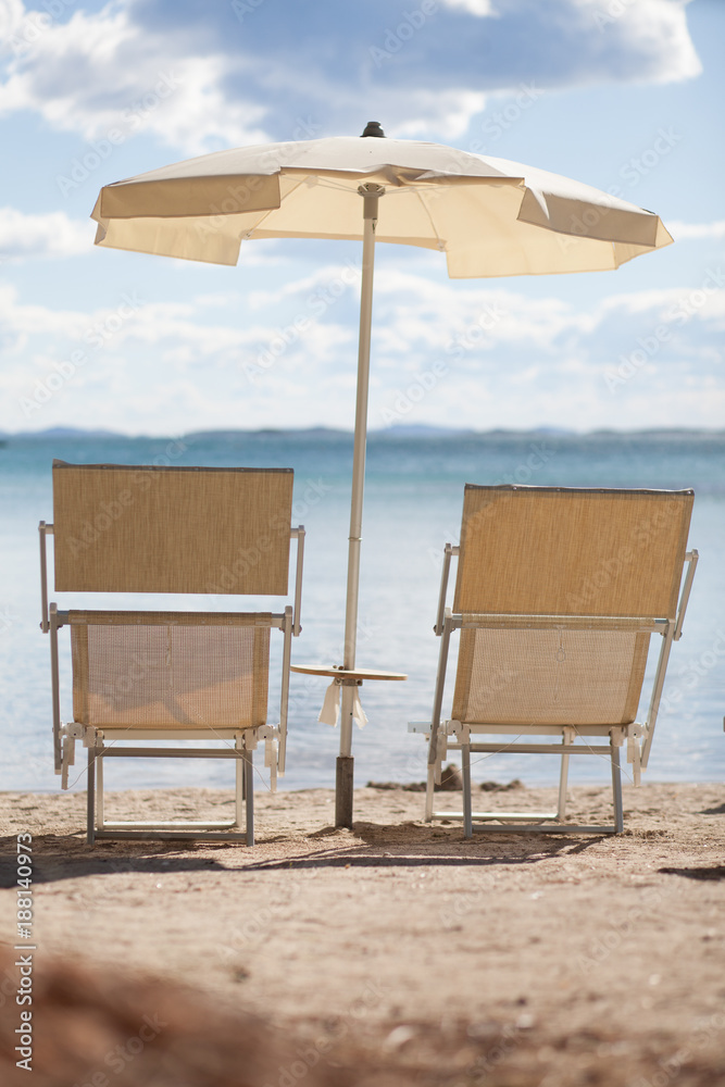 beach with sun umbrella and two lounge chairs