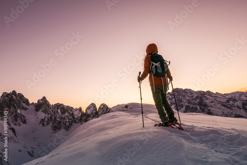 Young woman explorer hiking in snowshoes at the top of the mountain