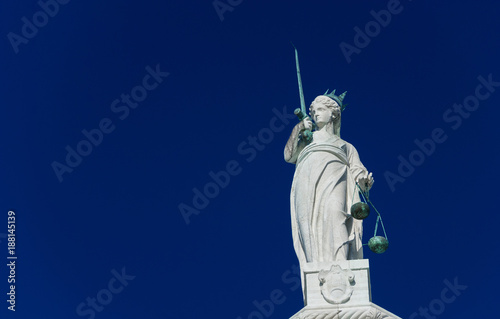 Goddess of Justice statue holding balance scales and sword (with copy space)