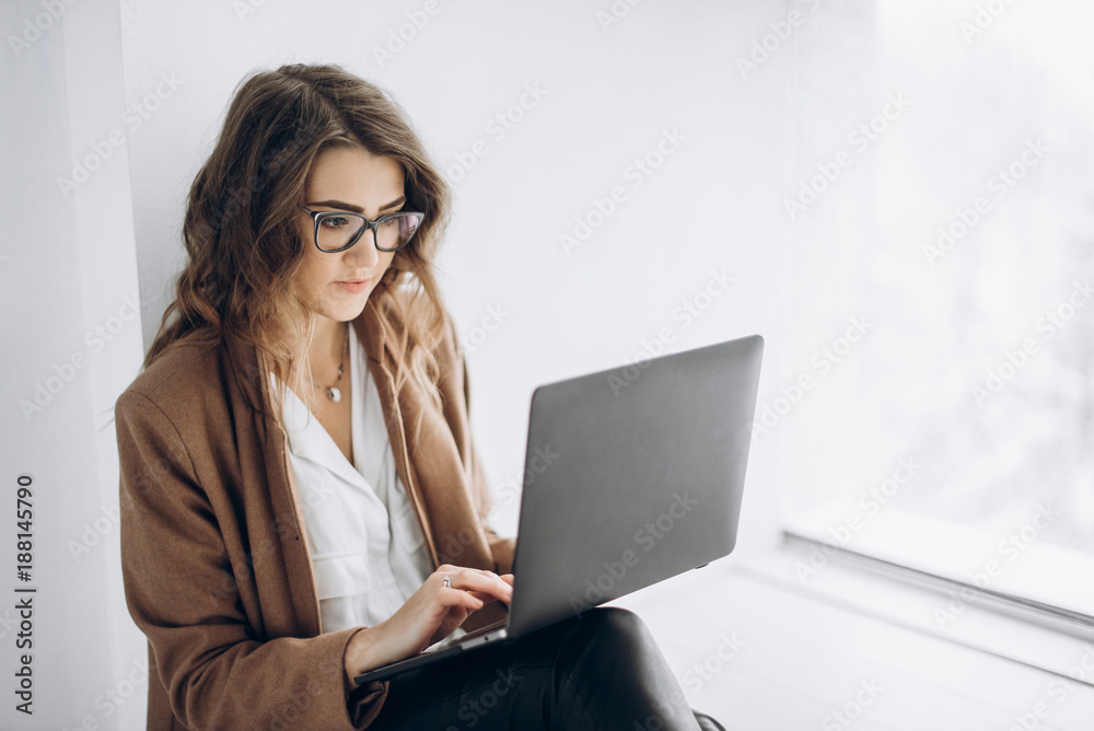Young beautiful business woman in glasses works on laptop in her office Young beautiful business woman in glasses works on laptop in her office