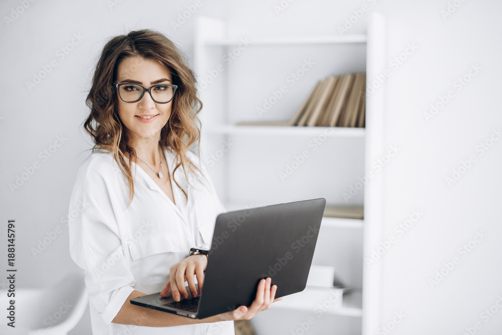 Young beautiful business woman in glasses works on laptop in her office Young beautiful business woman in glasses works on laptop in her office