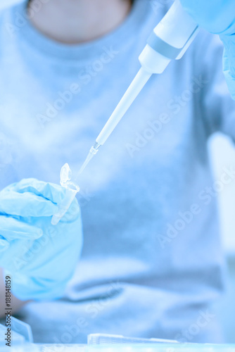 Scientist pipette dropping a sample into a test microtiter plate.