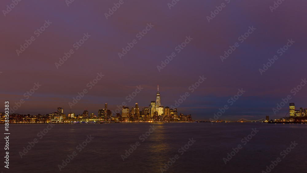 Low Manhattan skyline at night with reflection in Hudson River. Metropolis urban landscape in winter, New York, USA.