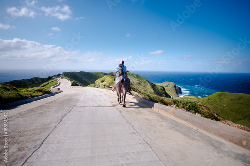 Farmer riding his Carabao at the hills of Batanes, Philippines photo