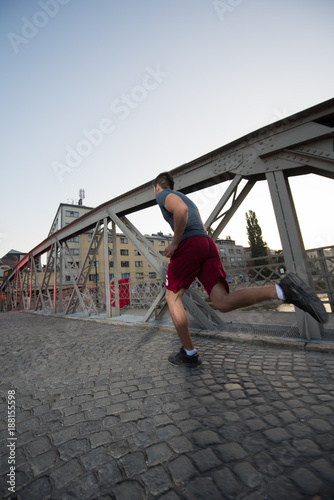 man jogging across the bridge at sunny morning