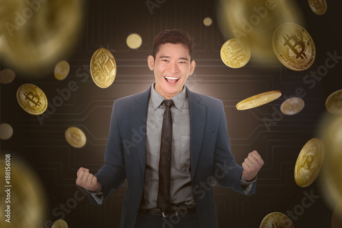 Happy asian businessman standing under a bitcoin rain