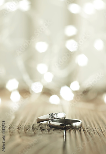 Two wedding rings place on wooden floor with light bokeh background.