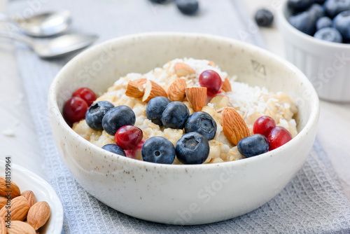 Oatmeal porridge with blueberries, cranberries and almonds in white bowl. Closeup view. Concept of healthy eating, dieting, healthy lifestyle
