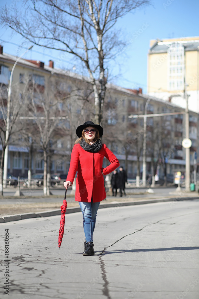 Pretty girl on a walk in red coat in the city