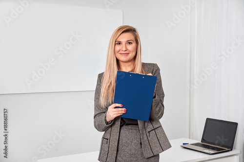business woman standing with clipping board in the office and ready to write something.