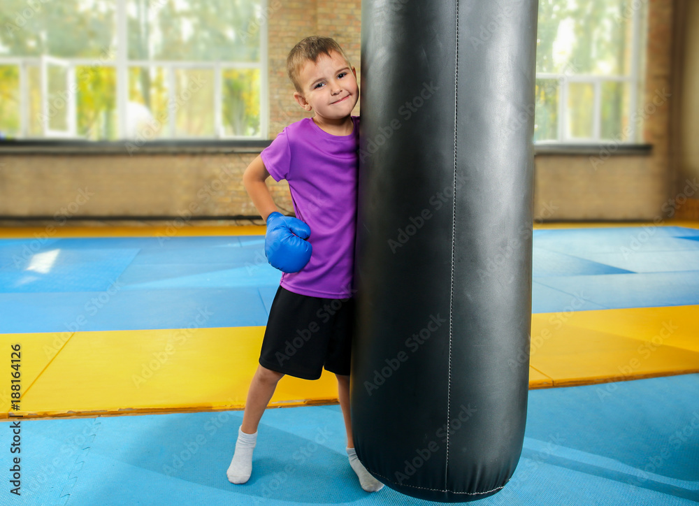 Cute little boy near punchbag in gym