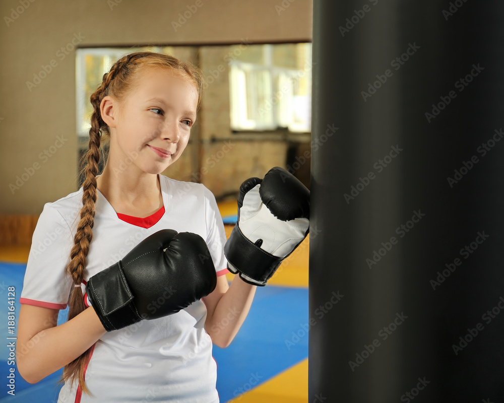 Cute little girl in boxing gloves indoors