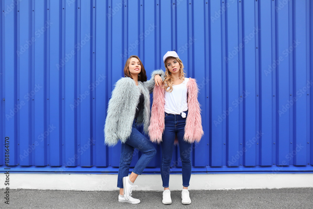 Two hipster girls near color wall outdoors