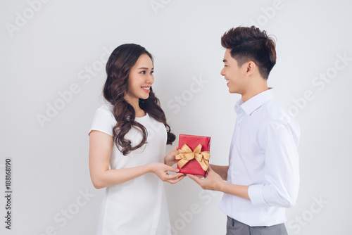 Love. Handsome young Vietnamese man giving present to beautiful woman at home