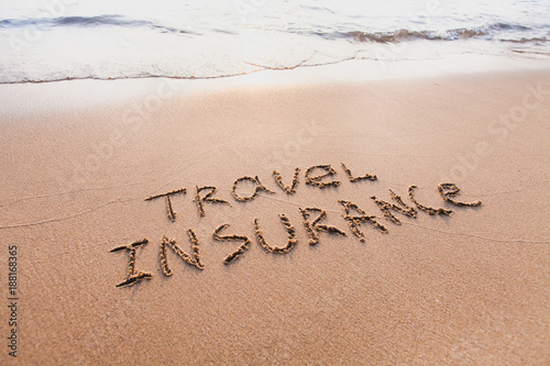 travel insurance concept, text words written on the sand