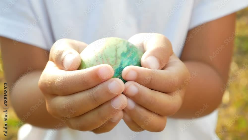 Close-up of children hand holding a easter eggs in sunshine background Close-up of children hand holding a easter eggs in sunshine background