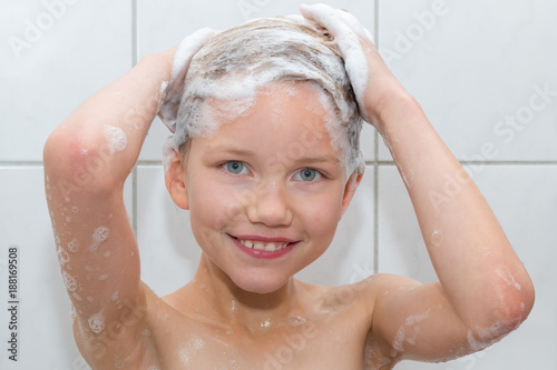 Ein 9 Jahre altes Mädchen steht in der Dusche und schäumt sich die Haare ein