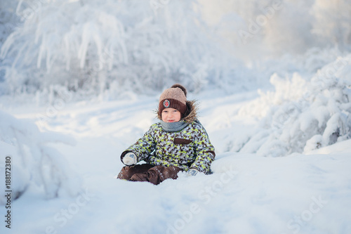 portrait of a five year old boy in the winter snowy forest photo