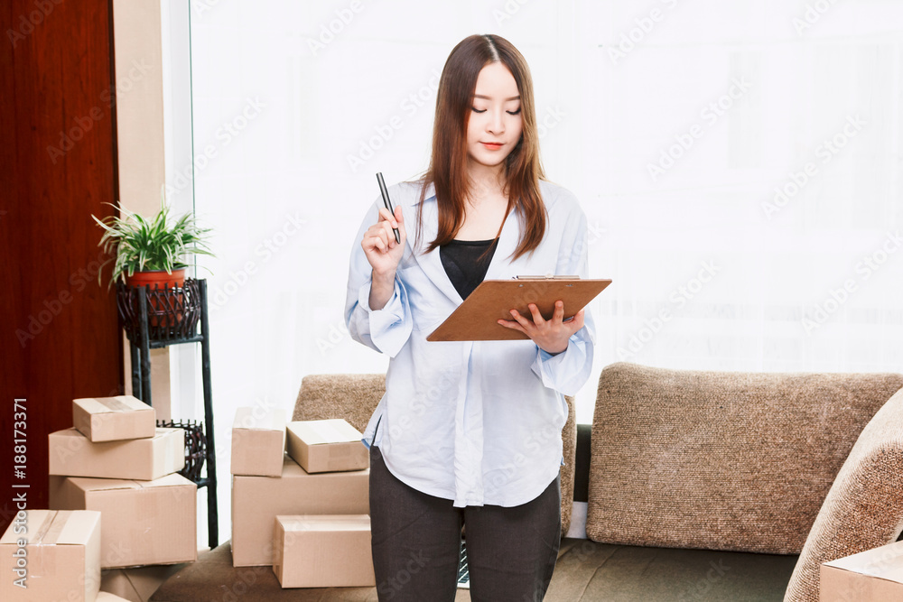 Young woman checklist with cardboard box at home - Business online and delivery concept