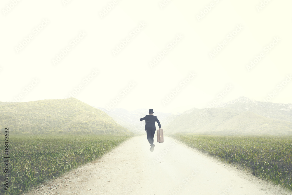 Obraz premium man with suitcase runs fast on a deserted road to an unknown destination