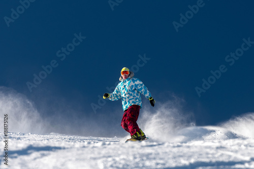 Snowboarder at ski slope against blue sky