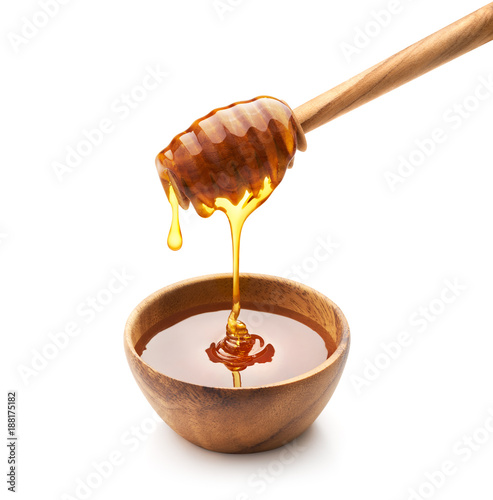 Honey dripping into wooden bowl isolated