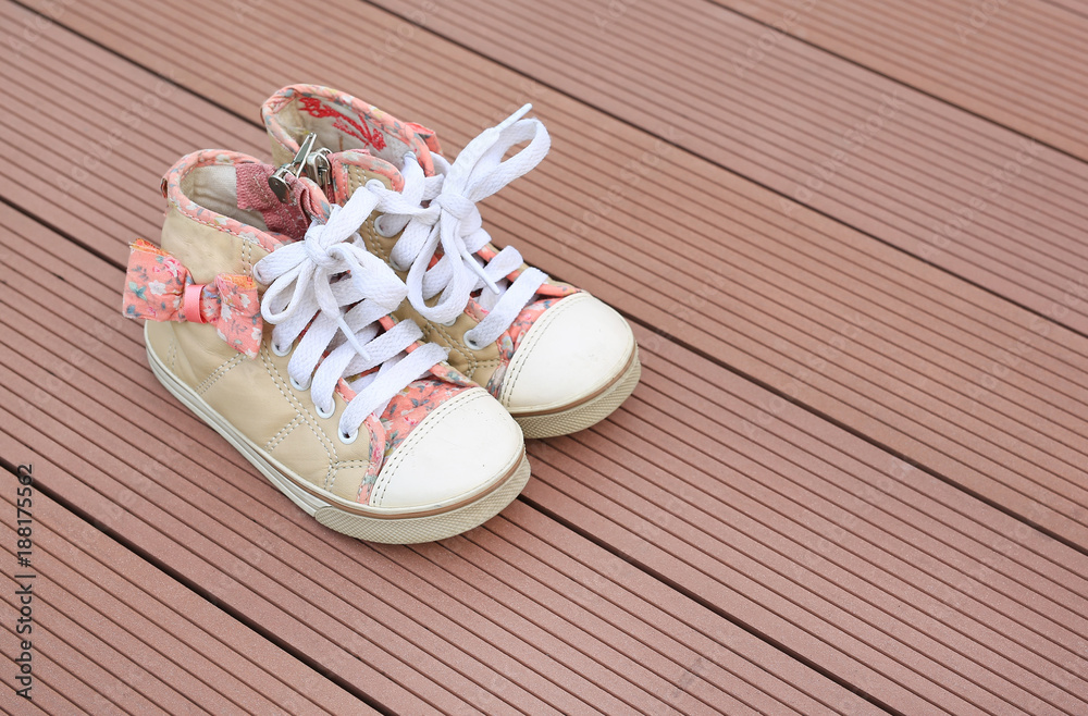 Pair of baby sneakers on wood plank background.