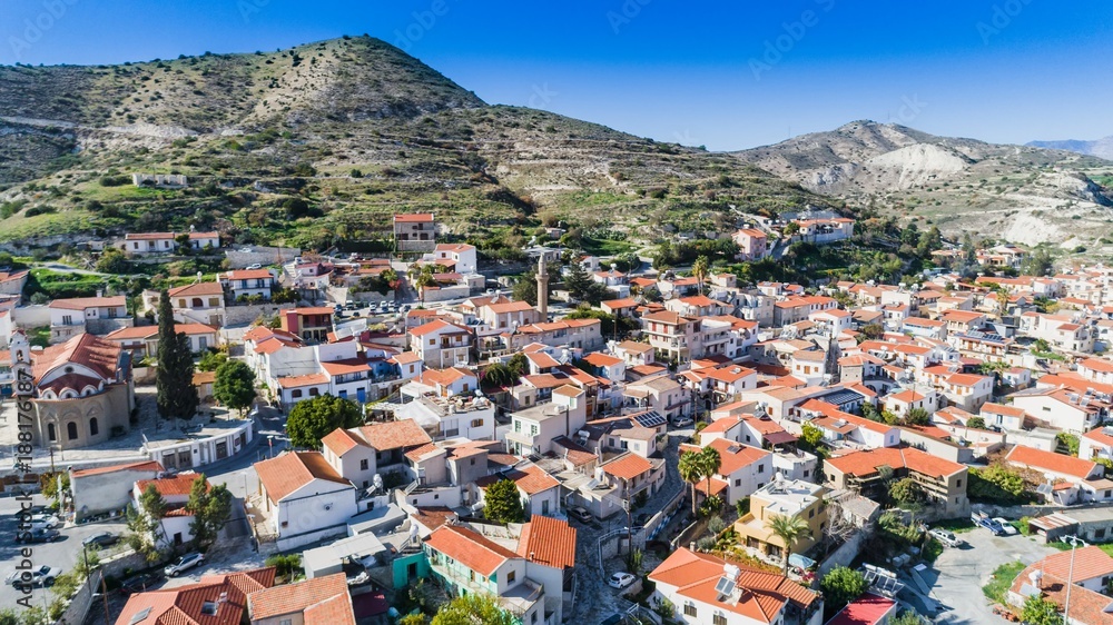 Aerial bird eye view of Kalavasos village valley, Larnaca, Cyprus. A traditional town with ceramic roof tiles houses, a greek orthodox christian church and muslim mosque around hills, from above.