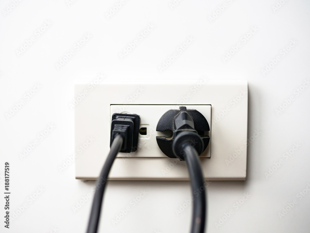 Black electric cord plugged into a socket Black electric cord plugged into a socket