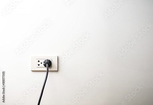 Black electric cord plugged into a socket