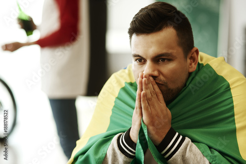 Fotografie Nervous football fan with flag praying