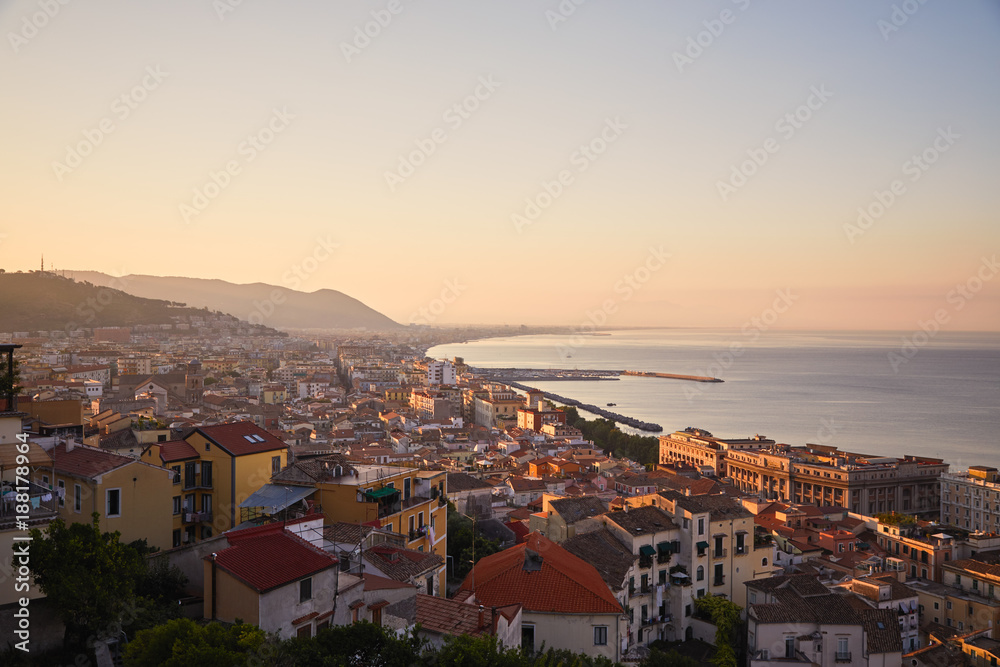 Beautiful panorama Italian seaside town - Salerno in sunrise time. The sun rises from behind the mountains and illuminates the city and the sea with its light