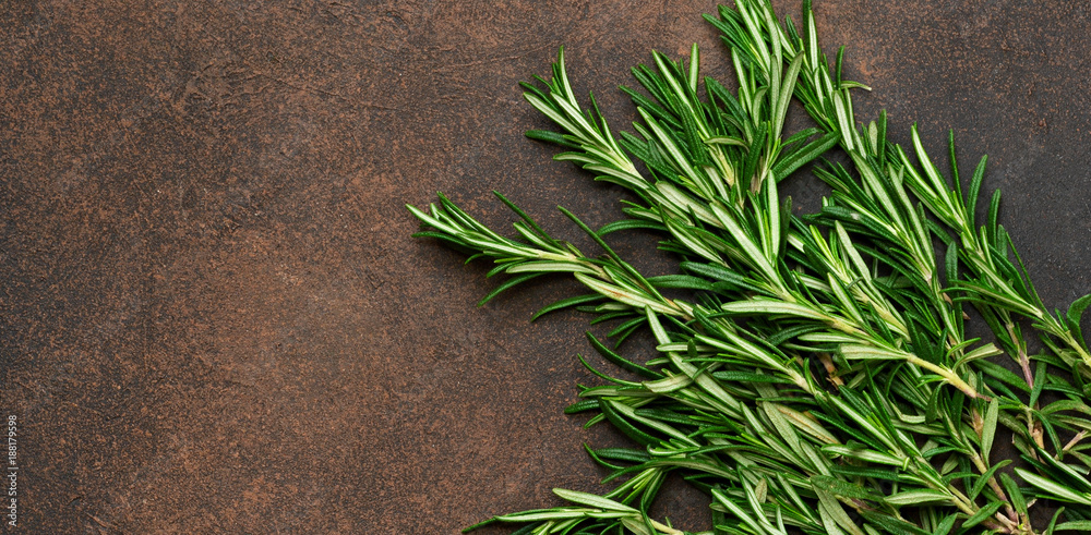 A fresh bunch of rosemary on a brown concrete background. Organic food background. - obrazy, fototapety, plakaty 