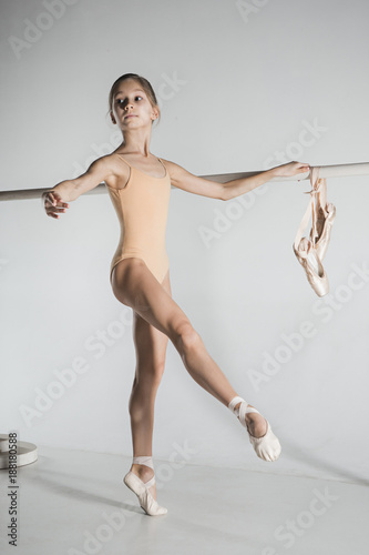 The girl is training near the ballet barre.