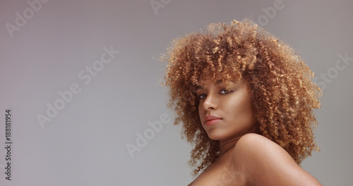 mixed race black woman with neutral makeup portrait. Curly hair ideal skin, studio, grey background