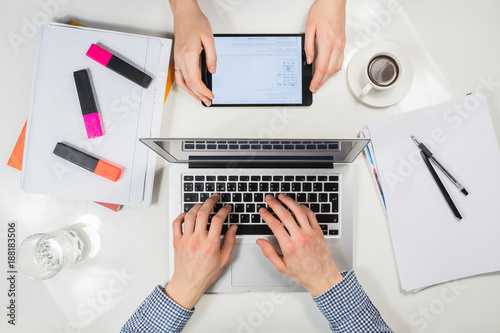 Modern workplace top view. male and female hands working with tablet and laptop pc at modern white workplace desktop together on financial, business or school activity.