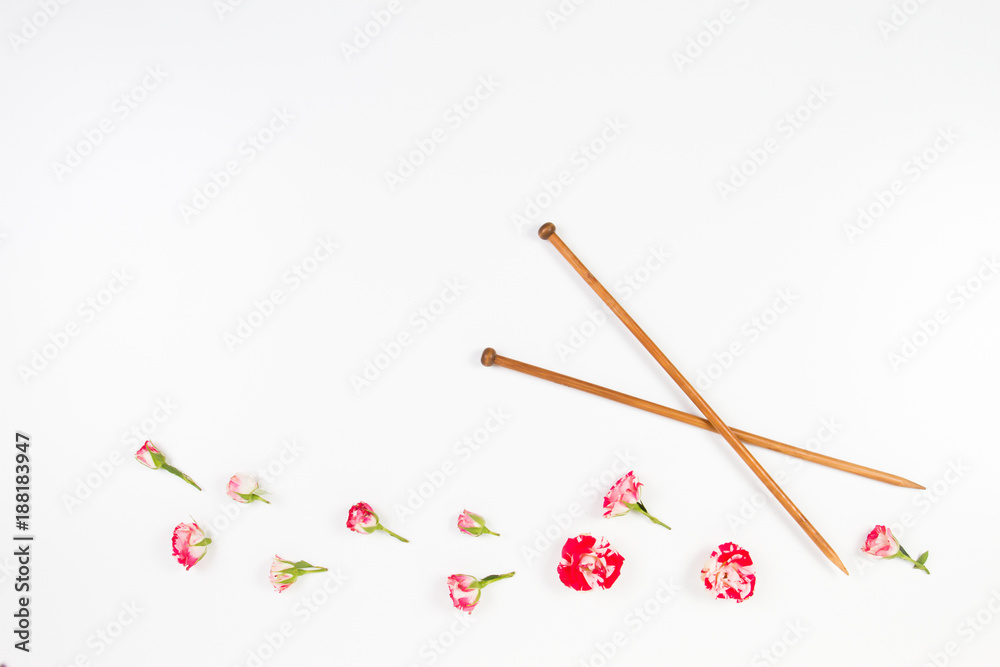 Wooden knitting needles and fresh roses on white background Wooden knitting needles and fresh roses on white background