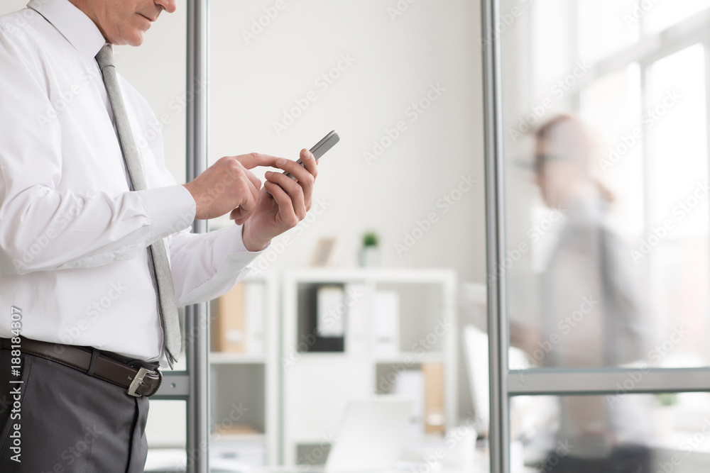 Director of business enterprise in shirt and tie holding smartphone and texting in office Director of business enterprise in shirt and tie holding smartphone and texting in office