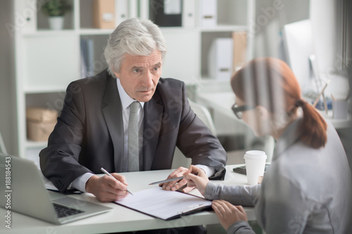 Картината върху платно Senior grey-haired director looking at his secretary while going to sign some pa