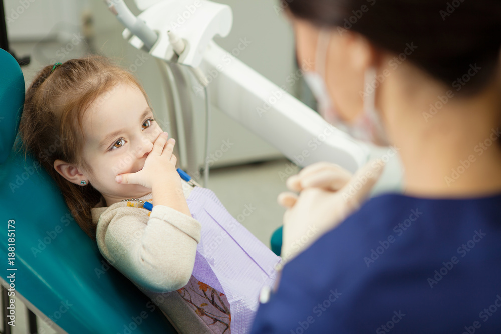 Child closes mouth with hand and sits in dentist chair Child closes mouth with hand and sits in dentist chair
