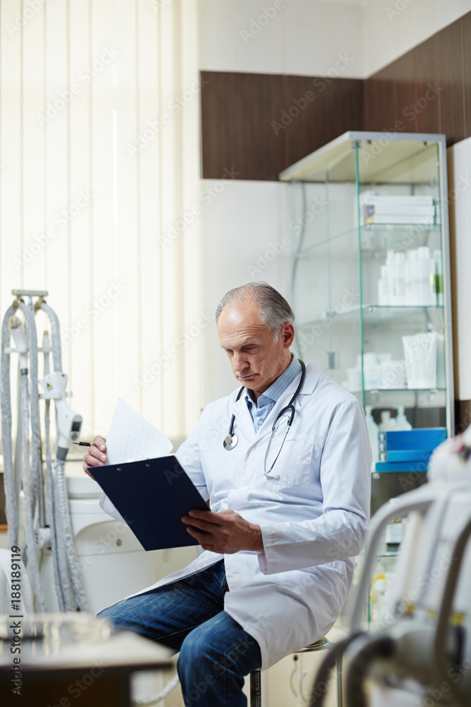 Contemporary clinician in whitecoat looking through medical documents in hospital Contemporary clinician in whitecoat looking through medical documents in hospital